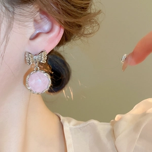 Close-up of pink resin round earrings with silver bow detail and twisted metal edge