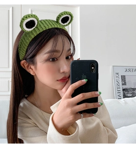 Detail of green knitted frog headband featuring cute 3D eyes and woven wool texture