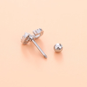 Detailed view of silver heart stud earring with zircon and star accents on skin background