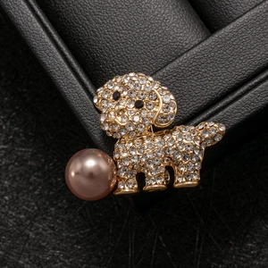 Macro view of crystal paved puppy brooch with a large rose gold pearl drop detail