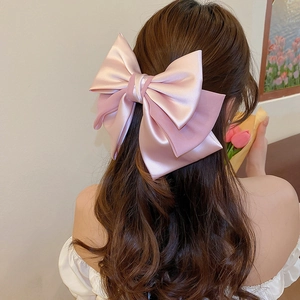 Detailed back view of large pink double-layer satin bow hair clip on long hair