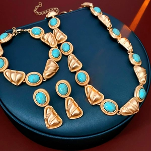 Parure de bijoux vintage en or avec pierres turquoise sur un présentoir bleu élégant