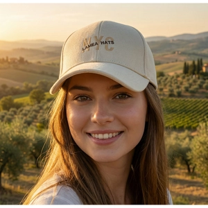 Close-up of NYC embroidery on a beige cotton baseball cap with a sunset background