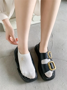 Close-up of white ankle socks with gold star embroidery worn with black sandals