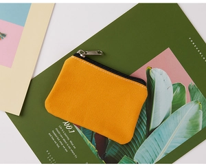 Minimalist ginger yellow canvas coin purse with silver zipper on a magazine background