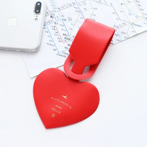 Detail view of heart-shaped red leather luggage tag with gold lettering on a travel map