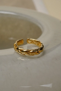 Nahaufnahme des goldenen gedrehten Rings mit poliertem Finish auf Marmor
