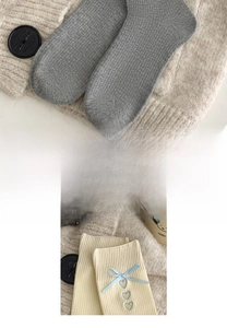 Detail von grauen und beigen Strickstrümpfen mit blauen Schleifen und Herzbestickung