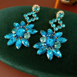 Détail de boucles d'oreilles vintage en fleurs de pierres bleues sur velours vert