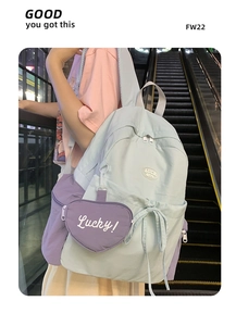 Detail of color-block nylon backpack with heart charm on a casual outdoor street setting