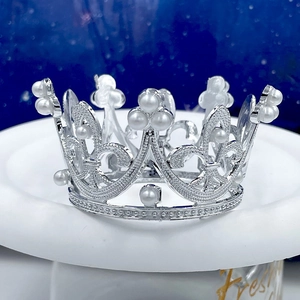 Dettaglio corona vintage in argento con incisioni traforate e perle bianche su base