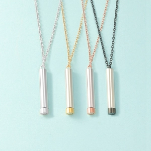 Close-up of cylindrical pendant necklaces in silver, gold, rose gold and black finishes