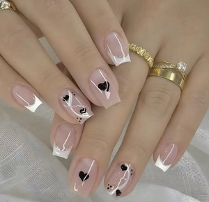 Short square press-on nails with pink base, white French tips, black hearts and dots