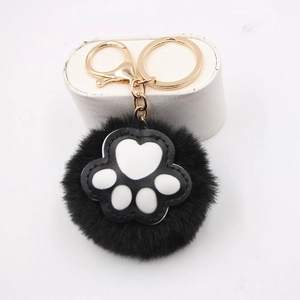 Cute black faux fur pompom keychain with white animal paw print on white stand