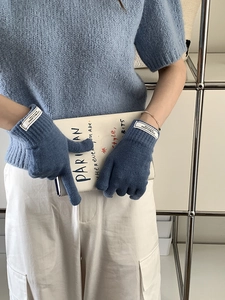 Detail of blue knitted touch-screen gloves with white cuff labels on model's hands