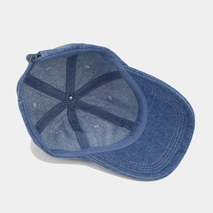 Inside view of a vintage blue denim baseball cap showing premium stitching and metal buckle