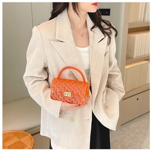 Orange clear jelly bag with quilted texture and gold chain strap shown on a beige blazer