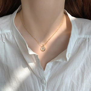 Close-up of gold tulip flower medallion necklace with white shell inlay on model