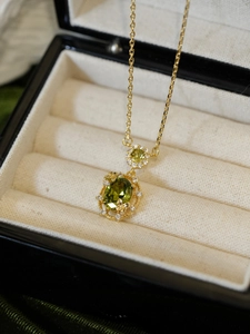 Macro shot of 18K gold plated necklace with green oval stone and golden butterflies
