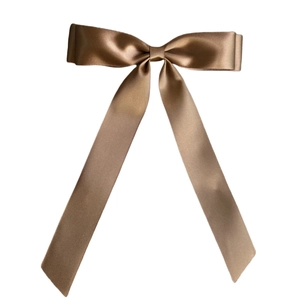 Close-up of champagne gold satin double bow hair clip with elegant long ribbon streamers