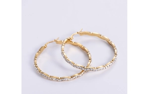 Detail of gold wave hoop earrings with clear crystals and sparkling rhinestones