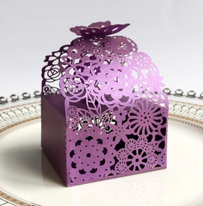 Macro detail of purple laser-cut wedding favor box with pearlized finish on white plate