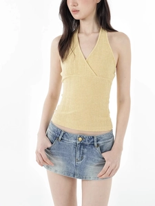 Detail of yellow ribbed knit halter top with V-neck cross design and blue denim mini skirt
