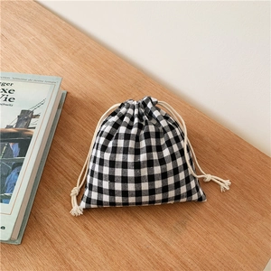 Minimalist black and white checkered cotton linen drawstring storage bag on wooden desk