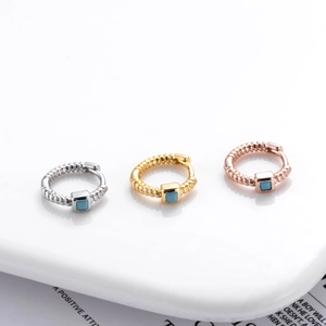 Detailed macro view of three textured huggie earrings in silver, gold and rose gold finishes