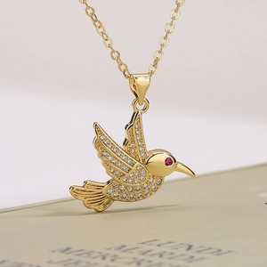 Dettaglio ravvicinato della collana colibrì dorata con cristalli e occhio in gemma rossa