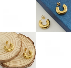 Detailed macro view of gold U-shaped earrings with ribbed texture and polished finish