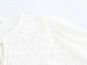 Detail of white lace top showing shoulder design and size S label with tassel accents