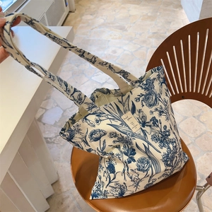 Detail of a vintage floral canvas tote bag with blue patterns on a stylish wooden chair