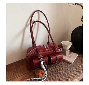 Detail of red glossy leather shoulder bag with pockets and a teddy dog pendant charm