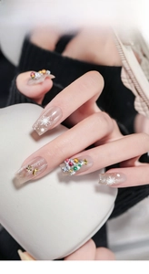 Close-up of Christmas nail art with 3D resin trees and snowflake charms on nude base