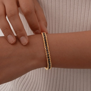 Close-up of a double-row gold chain bracelet featuring black zircon stones on a model's wrist