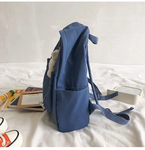 Side view of a minimalist blue canvas backpack in a campus lifestyle scene with accessories