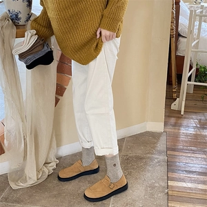 Close-up of khaki suede platform loafers with buckle detail and warm socks on feet