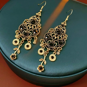 Detail of vintage gold earrings with black stones and tassels on a jewelry box