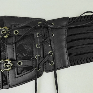 Détail d'une ceinture corset noire en dentelle avec boucles en métal et laçage ajustable