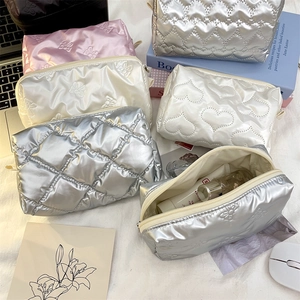Flat lay of quilted heart and butterfly makeup bags with silver cosmetic pouch detail