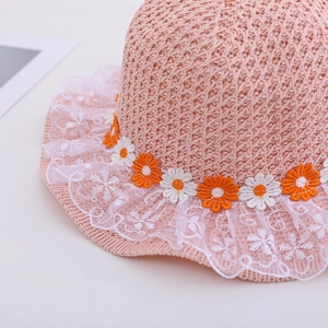 Close-up of pink straw sun hat featuring white lace trim and daisy embroidery details