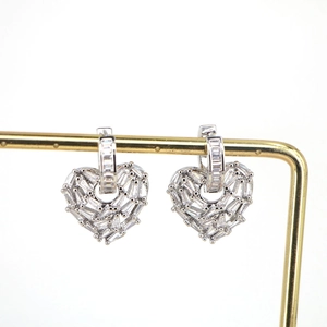 Detailed view of silver heart earrings with micro-pave zircons on a gold metal stand