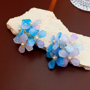 Détail de boucles d'oreilles fleuries dégradées avec perles sur un socle en pierre