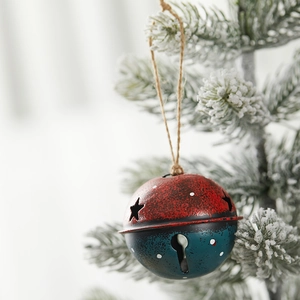 Vintage metal Christmas bell pendant in red and blue with star cutouts on tree branch