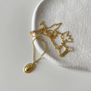 Detailed view of S925 sterling silver gold chain with polished oval pendant on tray