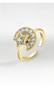 Macro detail of a rotating gold star and moon ring featuring inlaid sparkling zircon stones