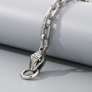 Detailed macro view of silver snake head clasp on polished stainless steel chain link