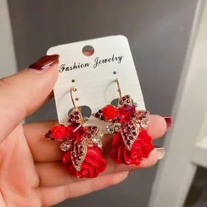 Close-up of red rose cross pendant earrings with ruby crystals and gold metal