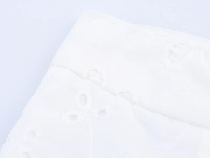 Detailaufnahme weißer Lochstickerei und floraler Muster auf Baumwollgewebe